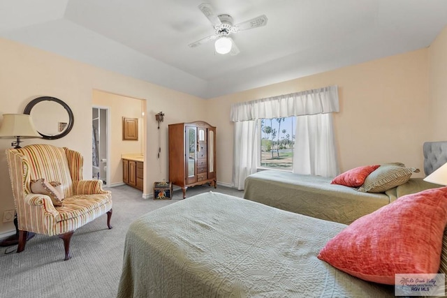 carpeted bedroom featuring a tray ceiling, baseboards, ceiling fan, and ensuite bathroom