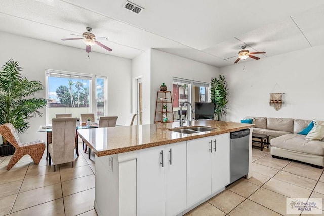 kitchen featuring a kitchen island with sink, white cabinets, sink, stainless steel dishwasher, and light tile patterned flooring