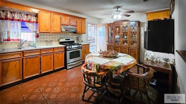 kitchen with sink, black fridge, a healthy amount of sunlight, and stainless steel range with gas stovetop