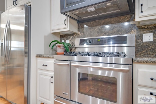 kitchen with backsplash, dark stone counters, ventilation hood, stainless steel appliances, and white cabinetry