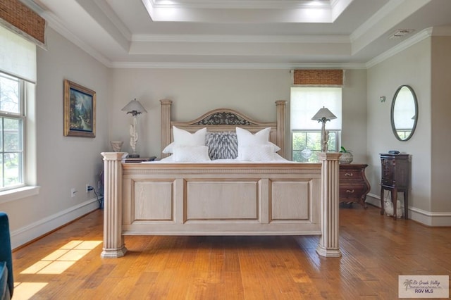 bedroom featuring a tray ceiling, ornamental molding, and hardwood / wood-style flooring