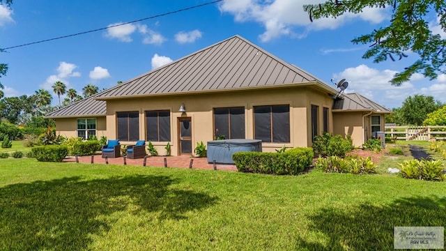 back of property featuring a yard and a hot tub