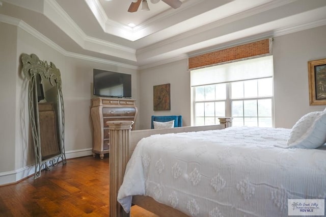 bedroom featuring dark hardwood / wood-style flooring, a tray ceiling, ceiling fan, and ornamental molding