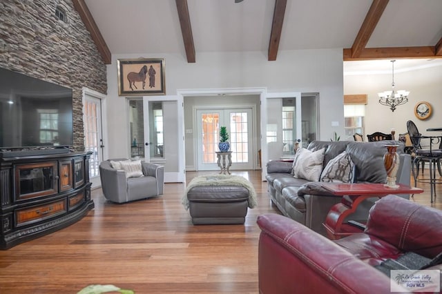 living room featuring hardwood / wood-style floors, french doors, a towering ceiling, beamed ceiling, and a notable chandelier