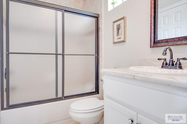 full bathroom featuring vanity, toilet, and bath / shower combo with glass door