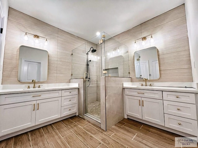 full bathroom with two vanities, a sink, tile walls, wood tiled floor, and a stall shower