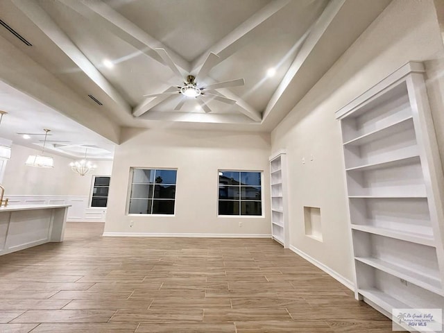 unfurnished living room featuring ceiling fan with notable chandelier, light wood-type flooring, visible vents, and built in features