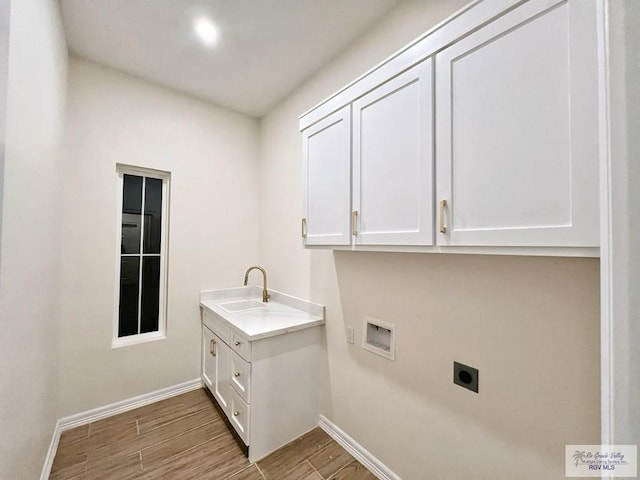 laundry room with cabinet space, a sink, electric dryer hookup, wood finished floors, and baseboards