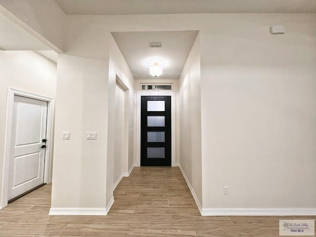 foyer entrance featuring baseboards, visible vents, and light wood-style floors