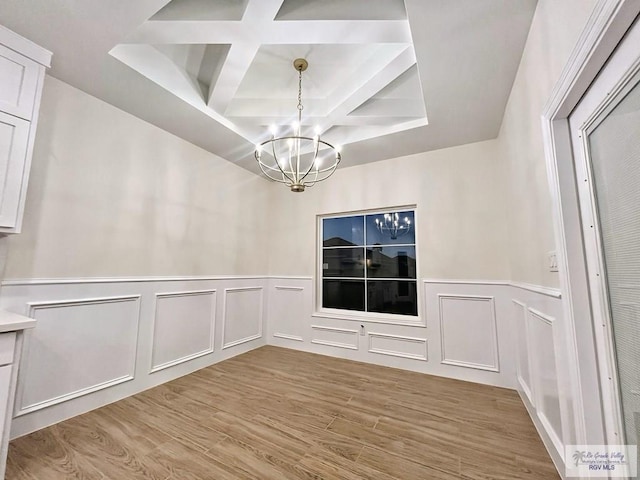 unfurnished dining area featuring a chandelier, a decorative wall, coffered ceiling, light wood-style floors, and beamed ceiling