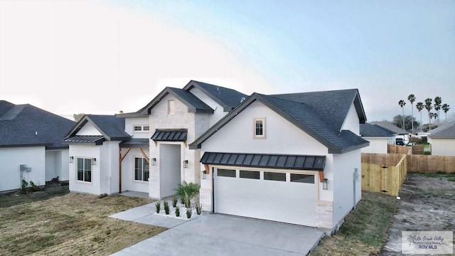 modern farmhouse style home with metal roof, a garage, fence, concrete driveway, and a standing seam roof