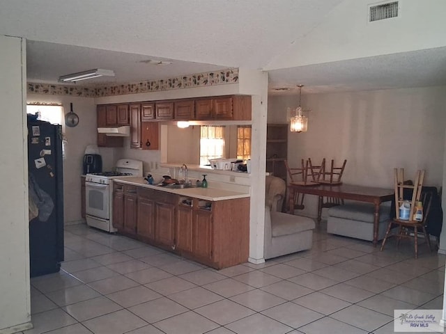 535 Windwood Way, Brownsville, TX 78526 - kitchen featuring white gas stove, light countertops, light tile patterned floors, under cabinet range hood, and vaulted ceiling