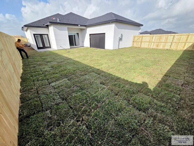 115 Finch Dr, Los Fresnos, TX 78566 - rear view of house featuring stucco siding, a fenced backyard, and a shingled roof