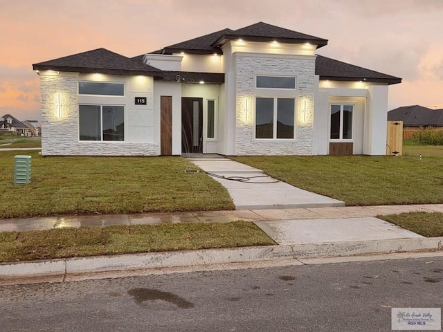 115 Finch Dr, Los Fresnos, TX 78566 - prairie-style home featuring stone siding, a front lawn, and roof with shingles