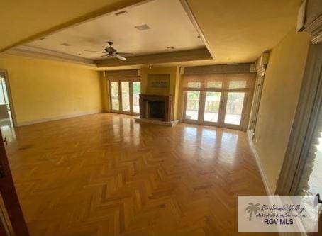 unfurnished living room featuring parquet flooring, french doors, a raised ceiling, and ceiling fan