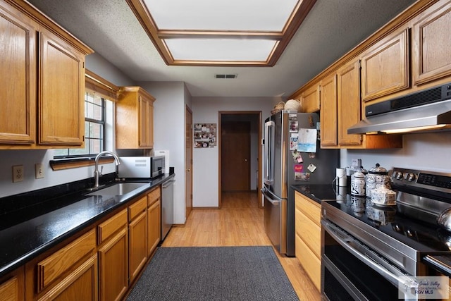 1675 Chipinque Dr, Brownsville, TX 78526 - kitchen with appliances with stainless steel finishes, under cabinet range hood, a sink, light wood finished floors, and brown cabinetry