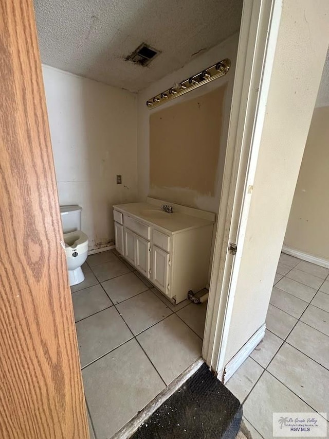 bathroom featuring toilet, a textured ceiling, tile patterned floors, and sink