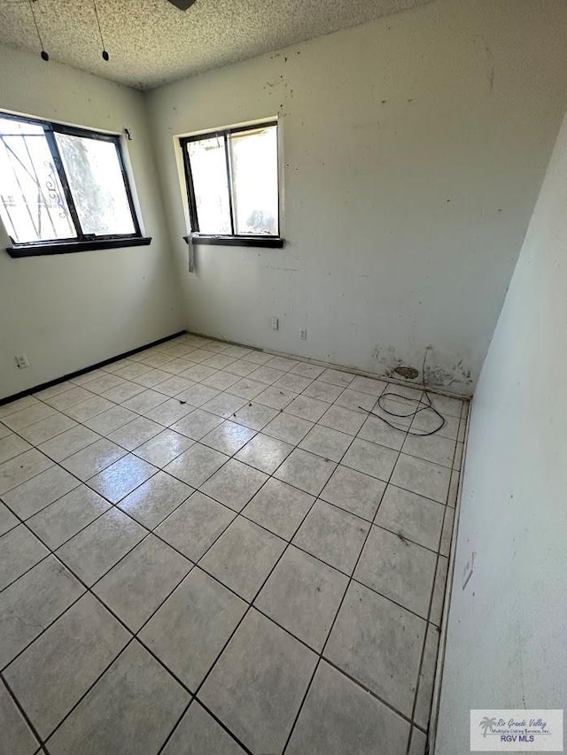 unfurnished room with ceiling fan, light tile patterned floors, and a textured ceiling