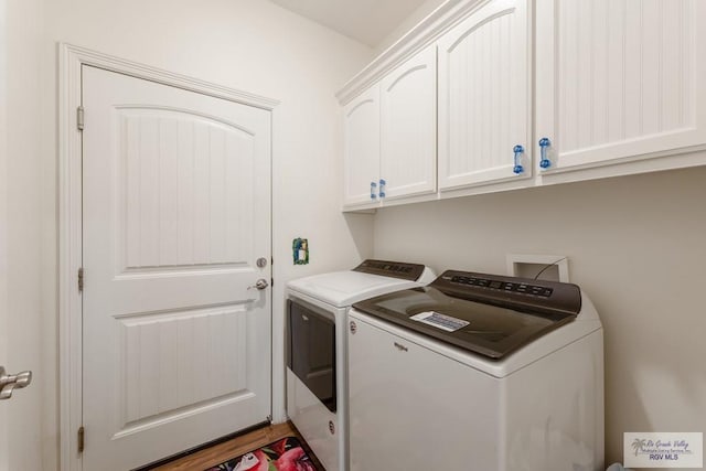 washroom featuring washing machine and dryer, cabinets, and hardwood / wood-style flooring