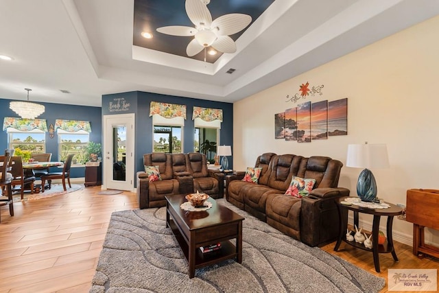 living room with hardwood / wood-style flooring, a raised ceiling, and ceiling fan