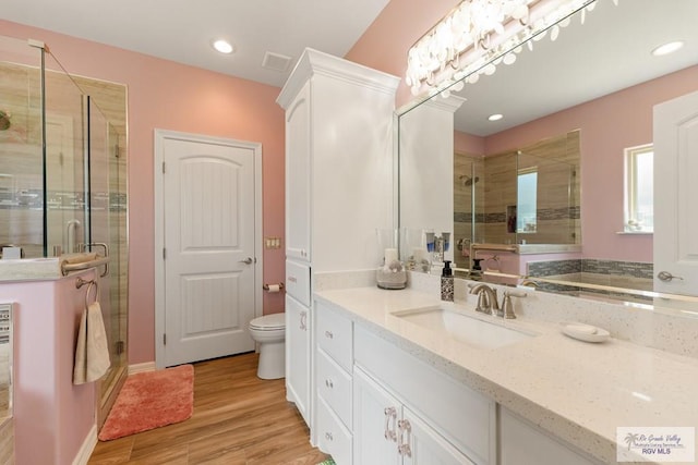 bathroom with vanity, hardwood / wood-style flooring, toilet, and a shower with door