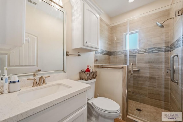 bathroom with vanity, toilet, and a shower with shower door