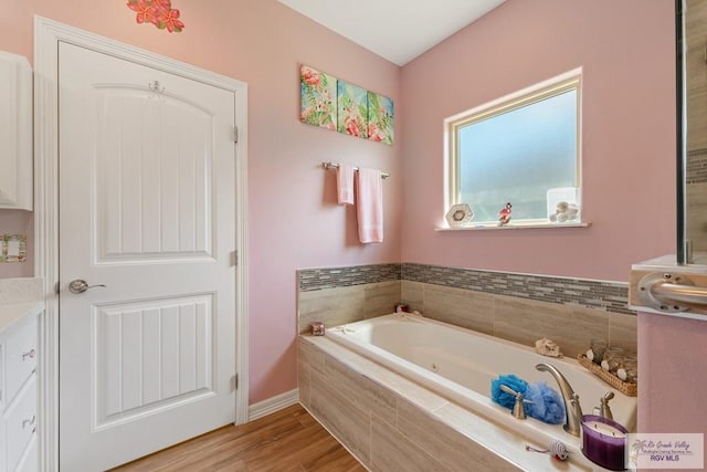 bathroom featuring tiled bath, hardwood / wood-style floors, and vanity