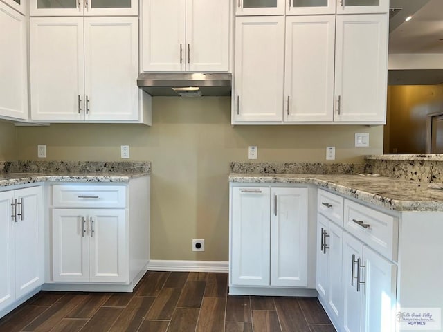 kitchen with light stone counters, white cabinetry, and dark wood-type flooring