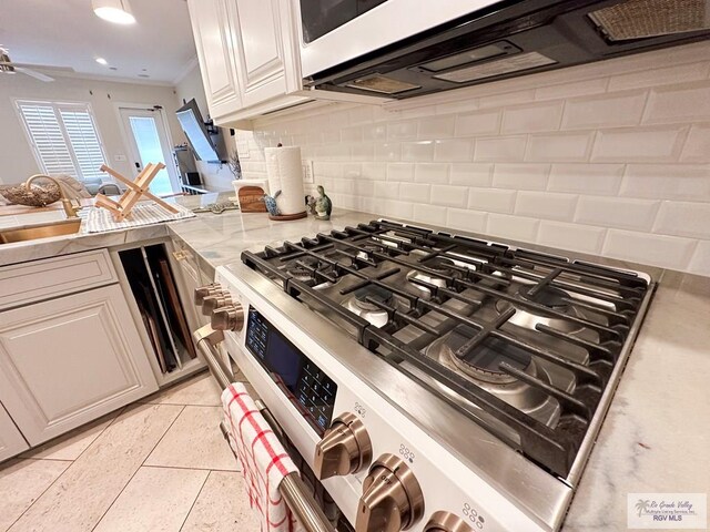 107 E Palm St Unit B, South Padre Island, TX 78597 - kitchen with stainless steel range with gas stovetop, crown molding, decorative backsplash, white cabinets, and a peninsula