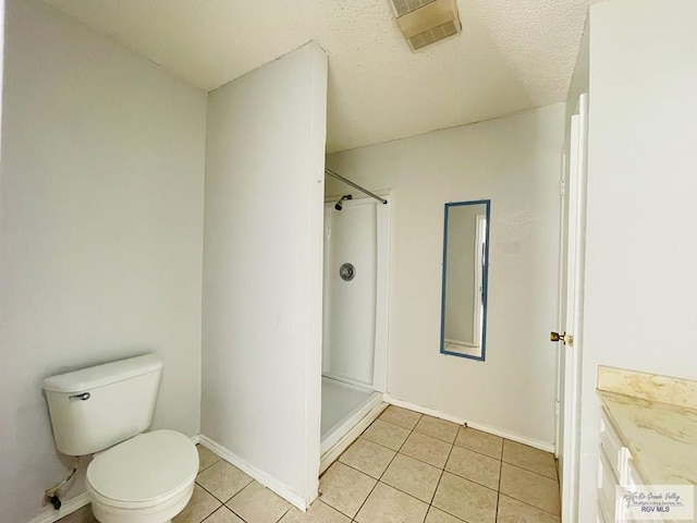 bathroom featuring tile patterned floors, a shower, a textured ceiling, toilet, and vanity