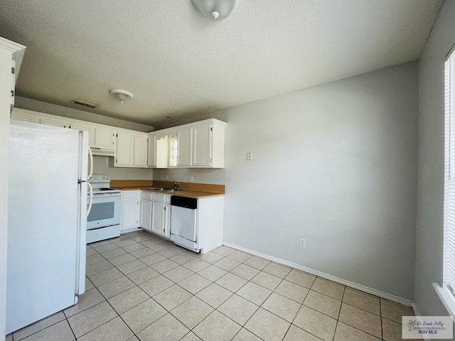 kitchen featuring white cabinets, light tile patterned flooring, white appliances, and sink