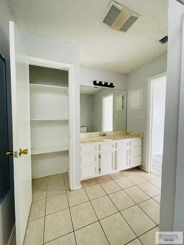 121 Las Palmas St, San Benito, TX 78586 - bathroom with a textured ceiling, vanity, tile patterned floors, and a healthy amount of sunlight