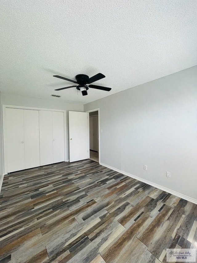 unfurnished bedroom featuring a textured ceiling, ceiling fan, a closet, and dark hardwood / wood-style floors