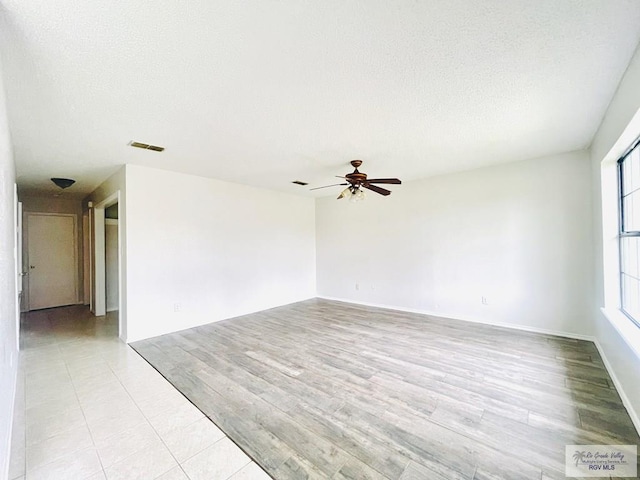 empty room featuring ceiling fan, light hardwood / wood-style flooring, and a textured ceiling