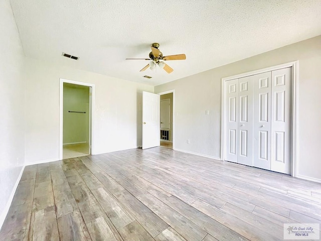 unfurnished bedroom featuring a textured ceiling, light hardwood / wood-style flooring, and ceiling fan