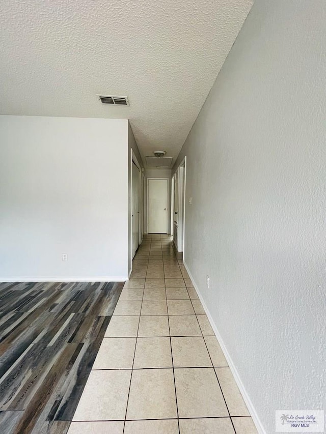 corridor featuring a textured ceiling and light hardwood / wood-style flooring