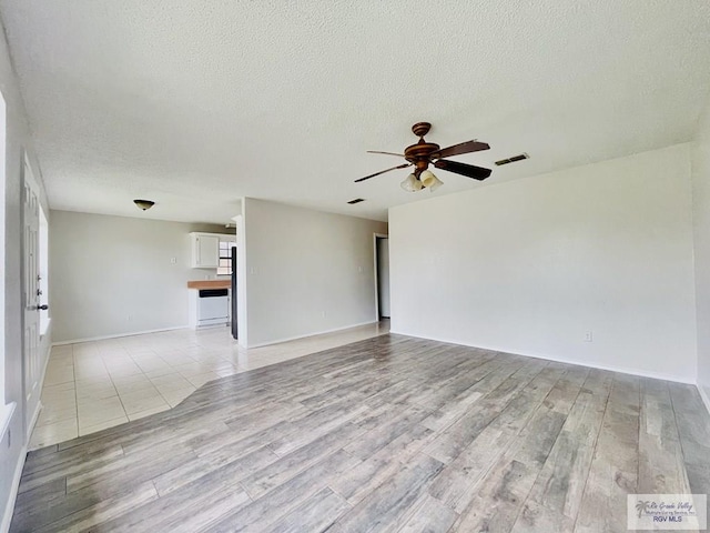 spare room featuring ceiling fan, light hardwood / wood-style floors, and a textured ceiling