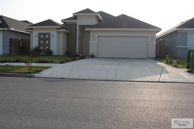 view of front facade featuring concrete driveway, an attached garage, fence, and stucco siding