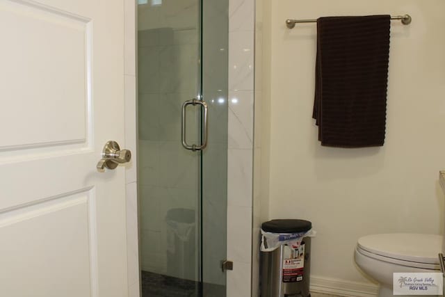 full bath featuring a stall shower, toilet, and baseboards