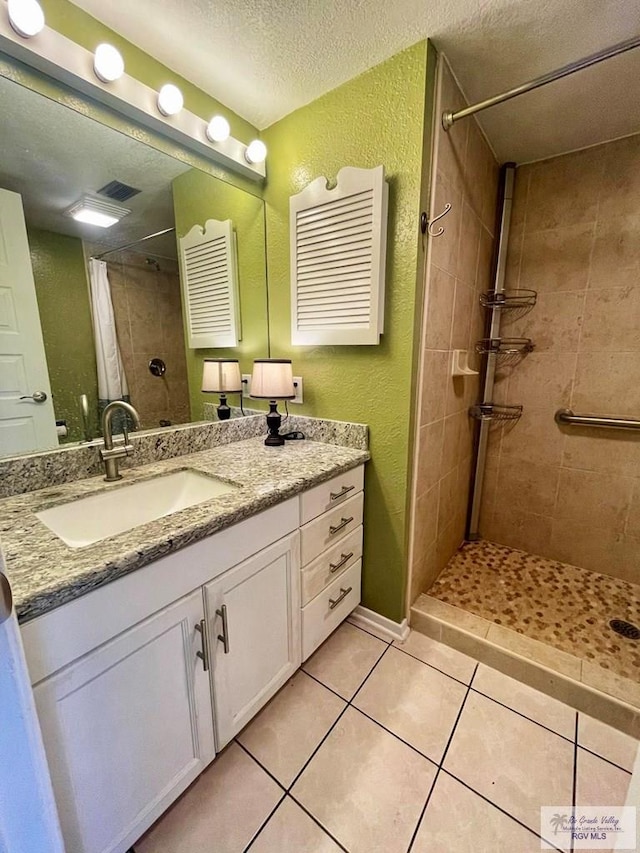 bathroom featuring tiled shower, vanity, a textured ceiling, and tile patterned floors