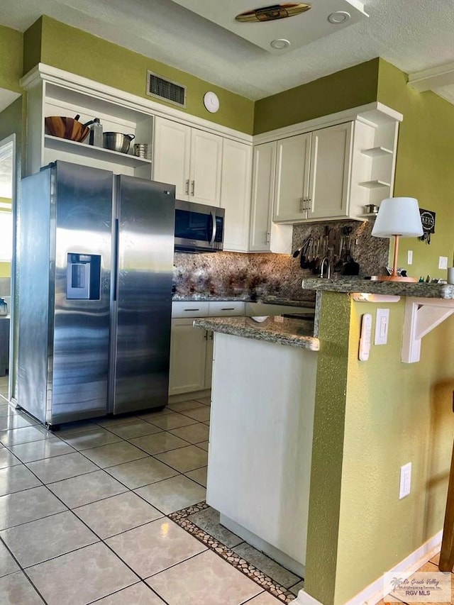 kitchen with backsplash, white cabinets, light tile patterned flooring, and appliances with stainless steel finishes