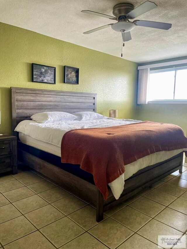 tiled bedroom with a textured ceiling and ceiling fan