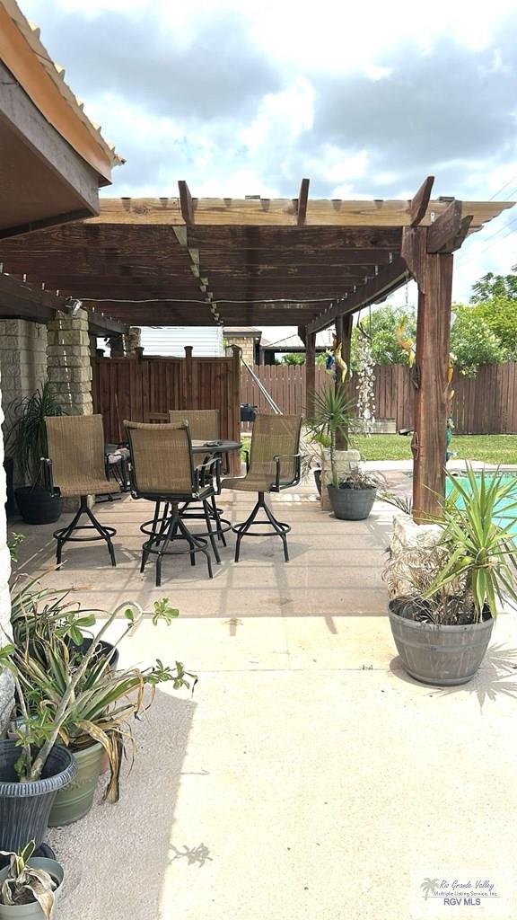 view of patio with a pergola, fence, outdoor dining space, and a wooden deck