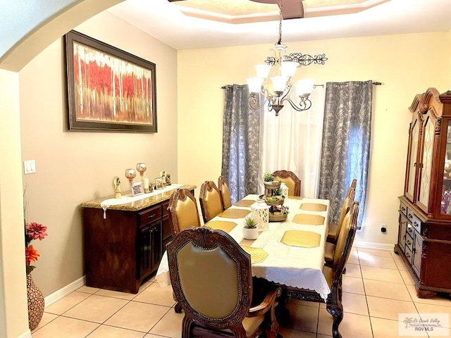 dining room with a chandelier, arched walkways, light tile patterned floors, and baseboards