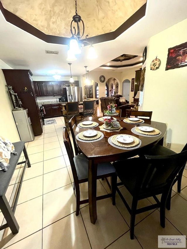 dining space featuring a tray ceiling and light tile patterned floors