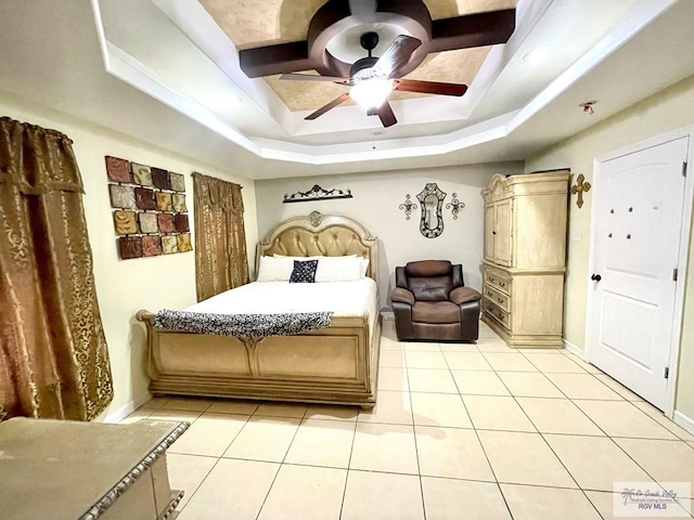 bedroom with a raised ceiling, light tile patterned flooring, baseboards, and ceiling fan