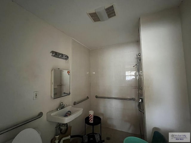 bathroom with toilet, sink, and tiled shower