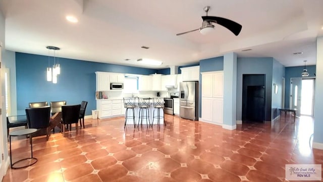 3429 E Country Club Dr, Edinburg, TX 78542 - kitchen with a ceiling fan, pendant lighting, stainless steel appliances, a kitchen bar, and white cabinetry
