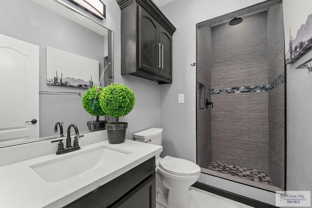 bathroom featuring a tile shower, vanity, and toilet