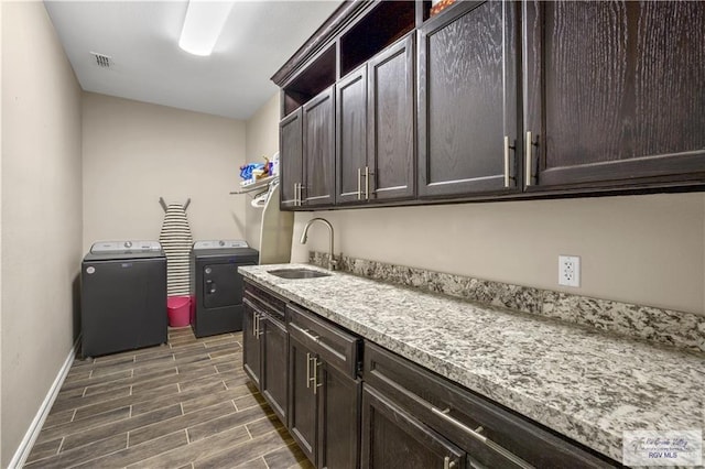 laundry area featuring washer and clothes dryer, sink, and cabinets